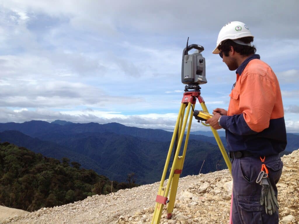 male surveyor operating total station overlooking deep valley