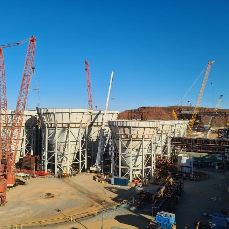 tanks in construction on site with multiple cranes