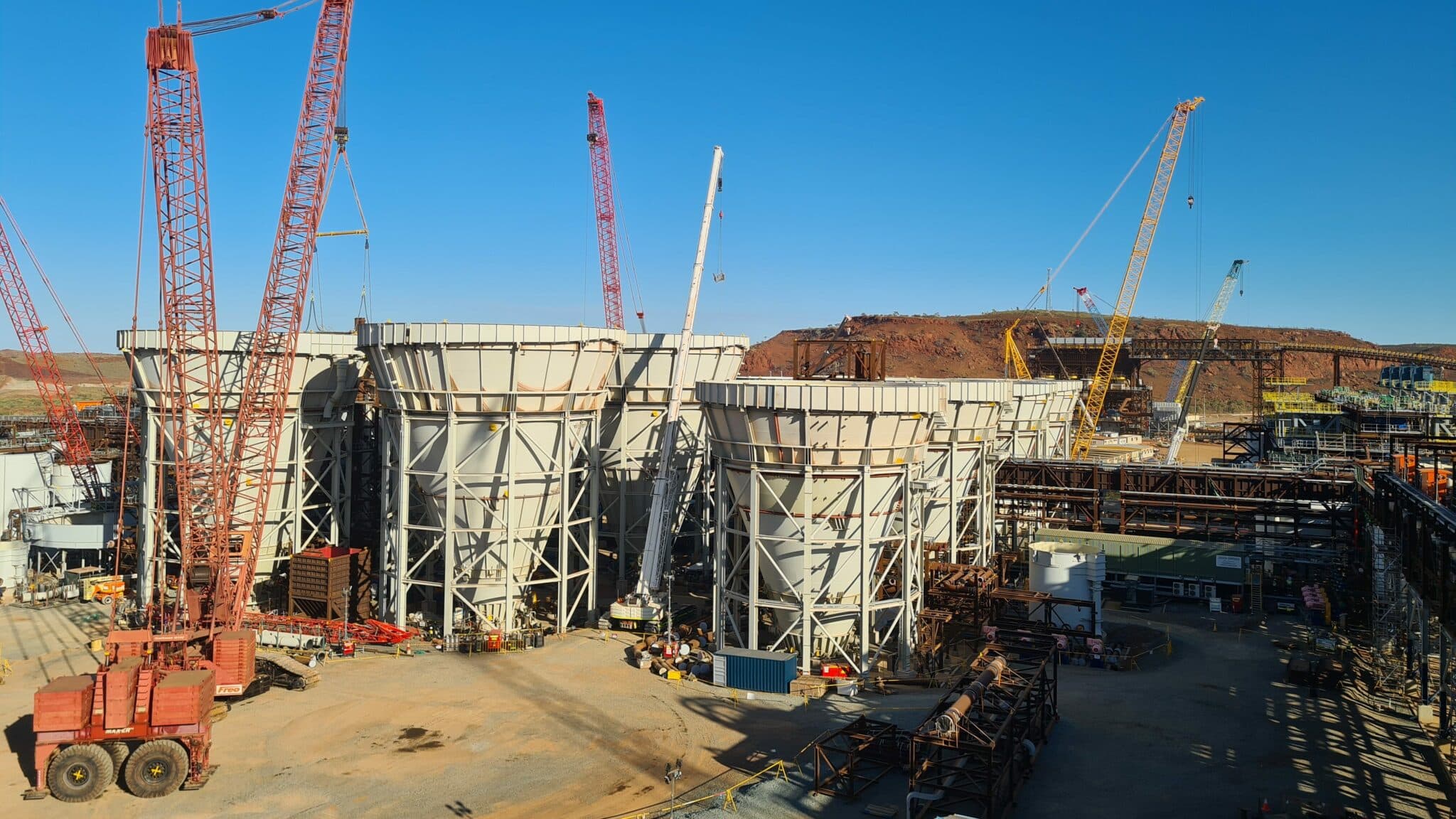 tanks in construction on site with multiple cranes
